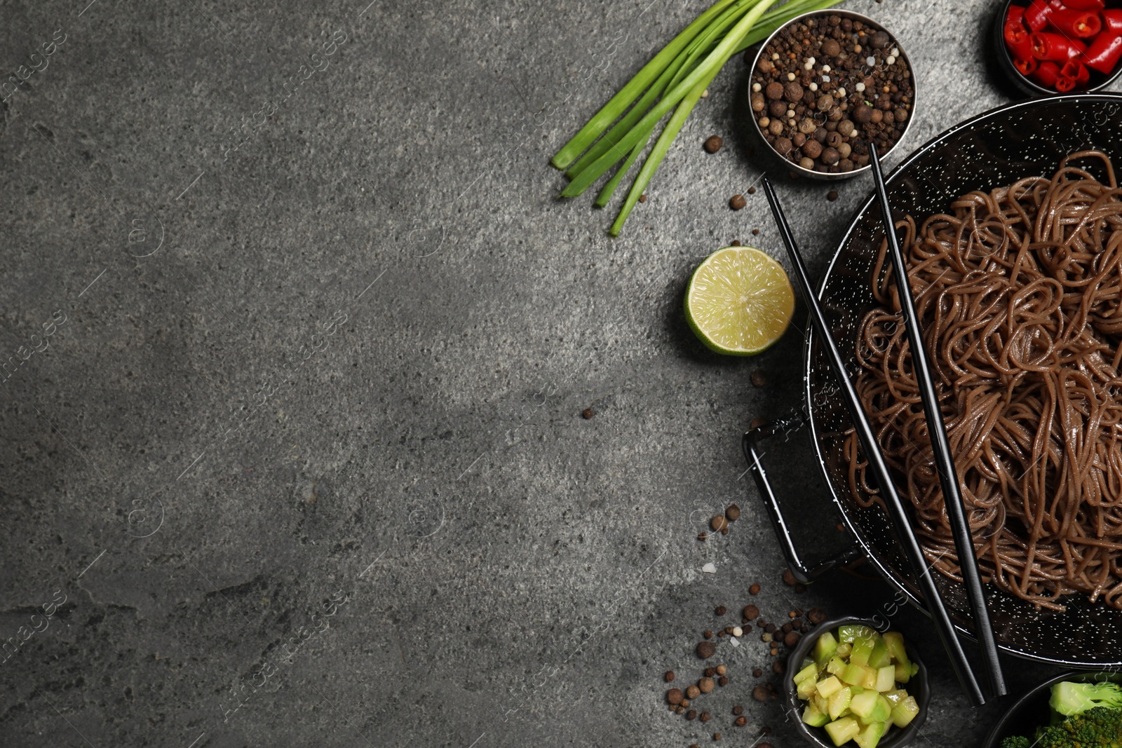 Photo of Wok with noodles and other products on grey table, flat lay. Space for text