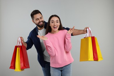 Excited couple with shopping bags on grey background