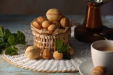 Photo of Aromatic walnut shaped cookies, mint and coffee on table. Homemade pastry filled with caramelized condensed milk