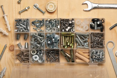 Organizer with many different fasteners and wrenches on wooden table, flat lay