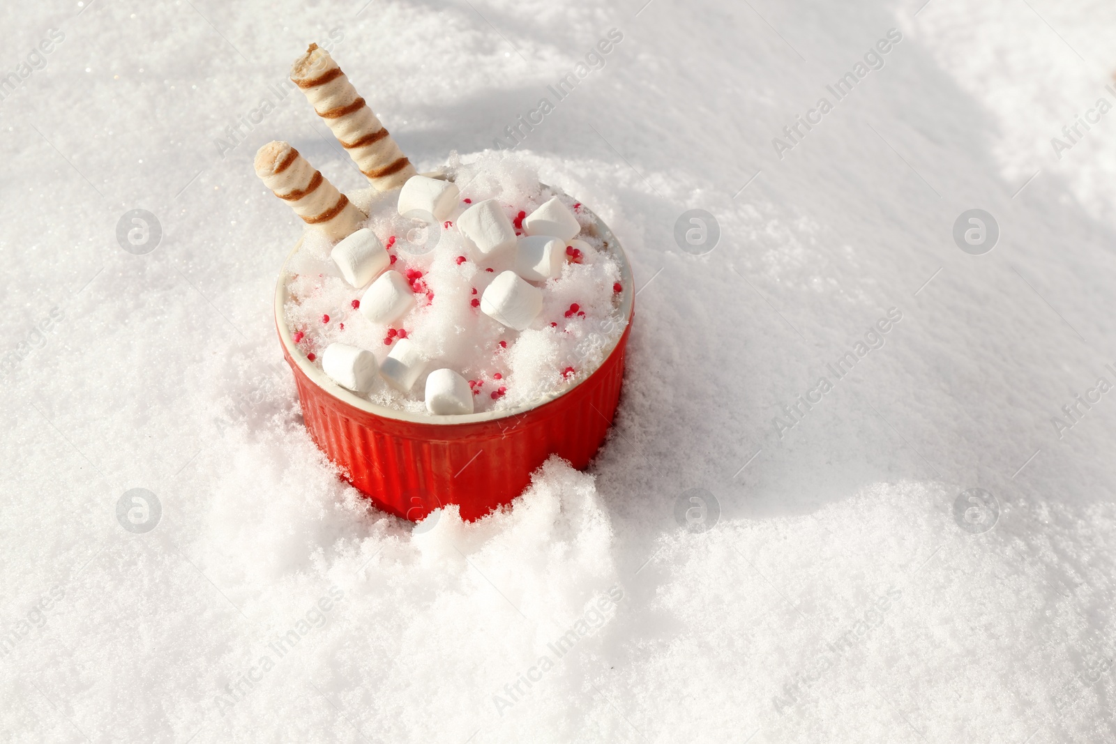 Photo of Bowl with tasty ice cream and waffle rolls on snow, space for text