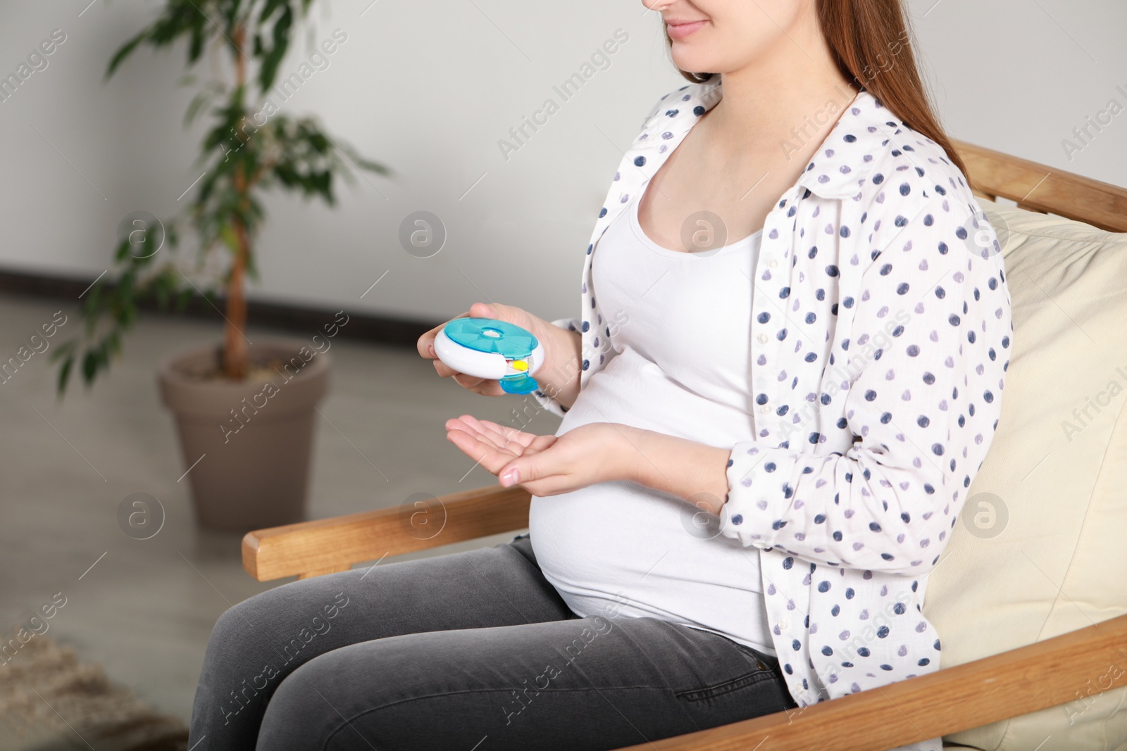 Photo of Pregnant woman taking pill from container at home, closeup