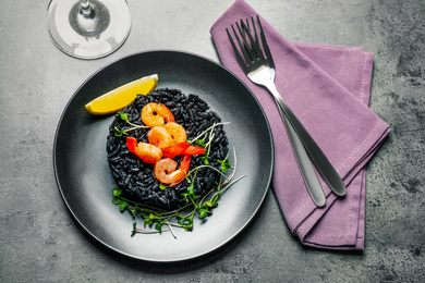 Photo of Delicious black risotto with shrimps served on grey table, flat lay