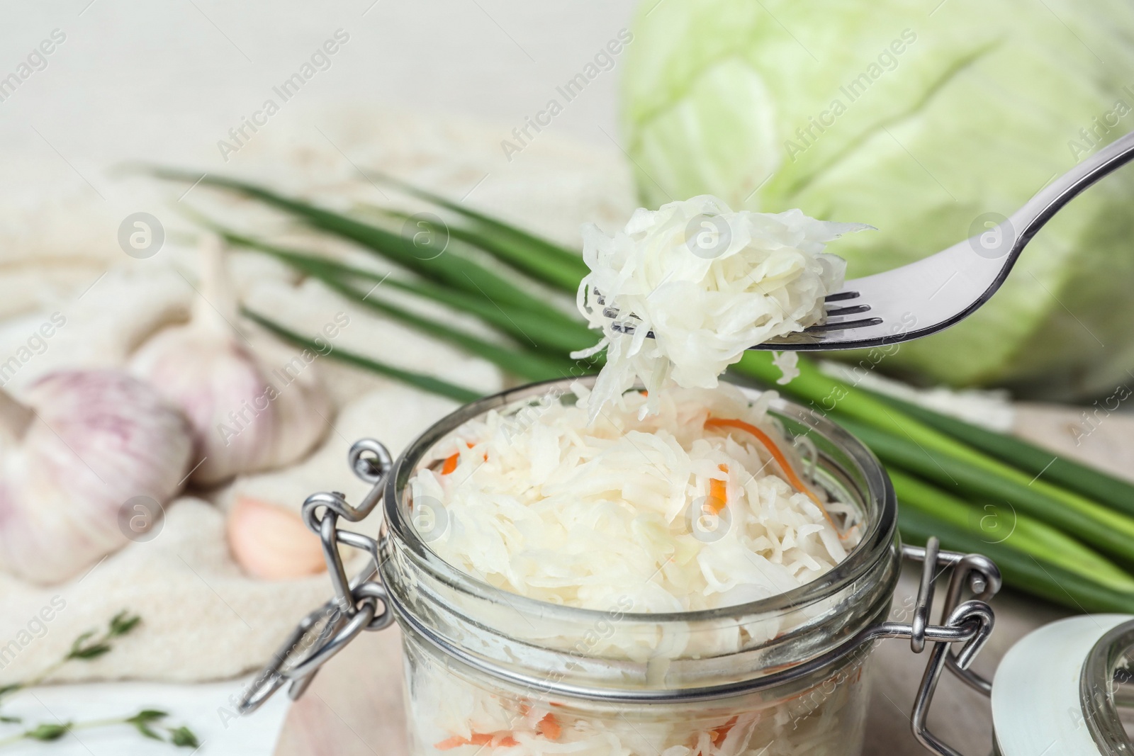 Photo of Fork with tasty fermented cabbage over jar, closeup