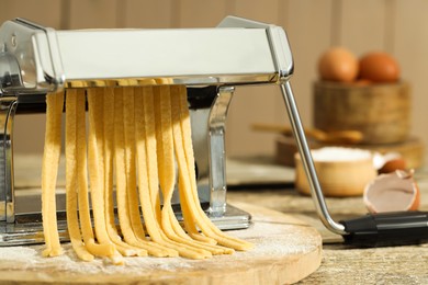 Photo of Pasta maker with raw dough on wooden table, closeup