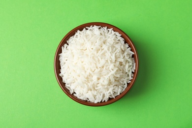 Bowl of tasty cooked rice on color background, top view