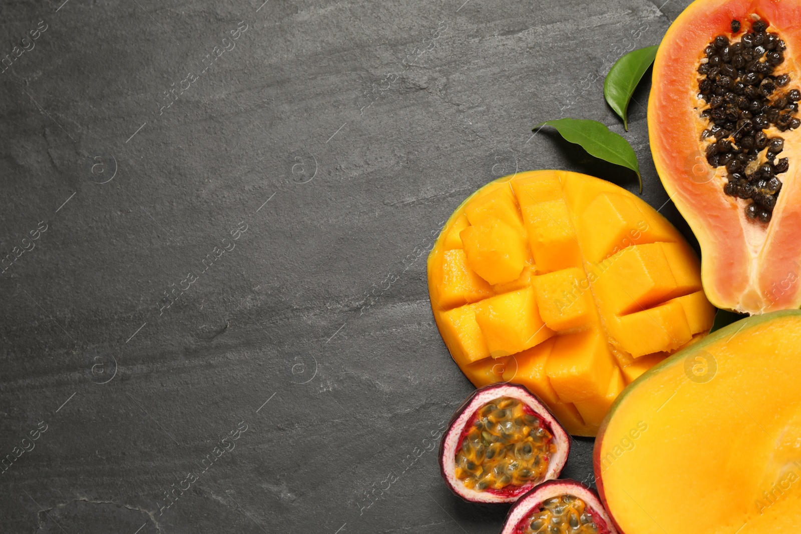 Photo of Fresh ripe papaya and other fruits on black table, flat lay. Space for text