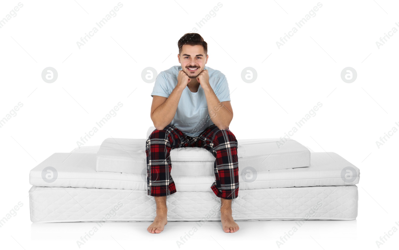 Photo of Young man sitting on mattress pile against white background