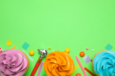 Flat lay composition with colorful birthday cupcakes on green background. Space for text