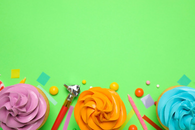 Photo of Flat lay composition with colorful birthday cupcakes on green background. Space for text