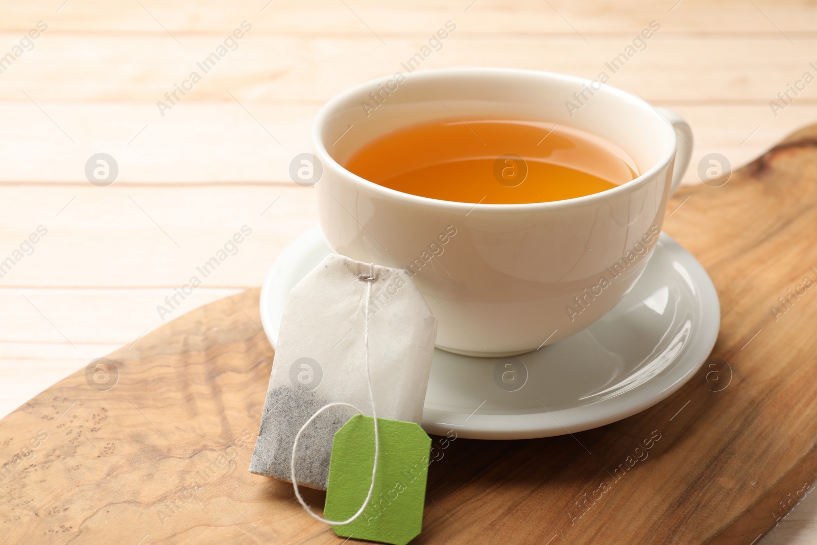 Photo of Tea bag and cup of hot beverage on light table, closeup. Space for text