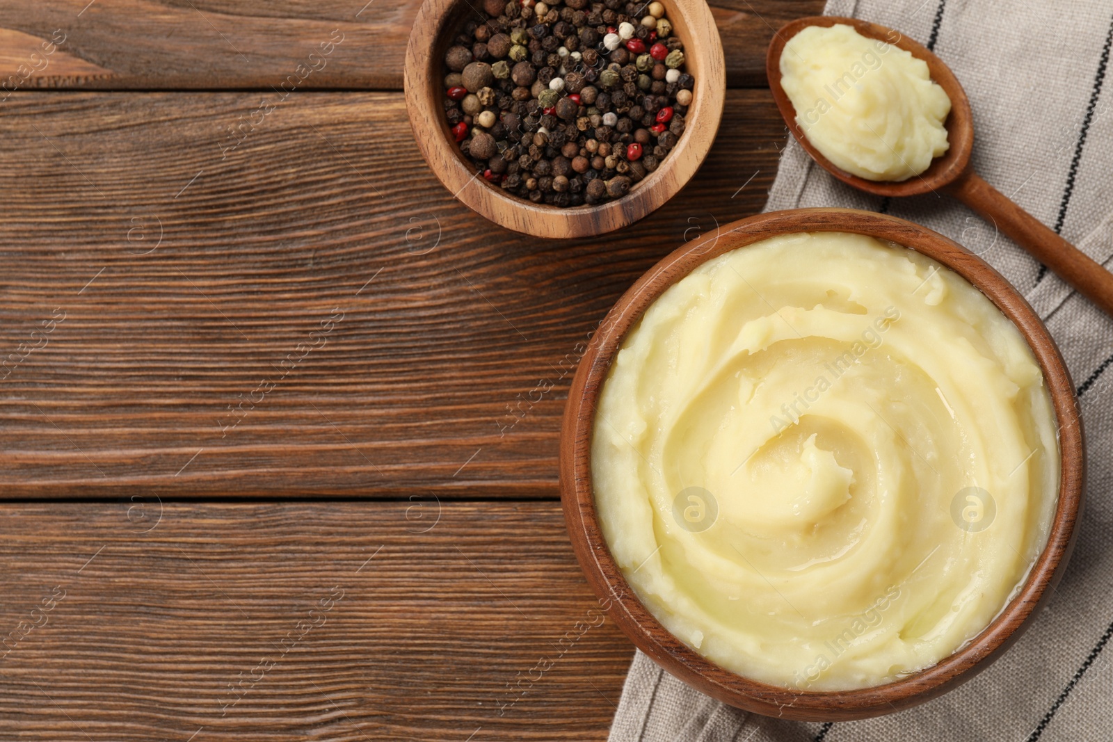 Photo of Bowl of tasty mashed potato and pepper on wooden table, flat lay. Space for text