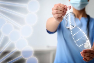 Scientist holding illustration of DNA structure in hands on burred background, closeup