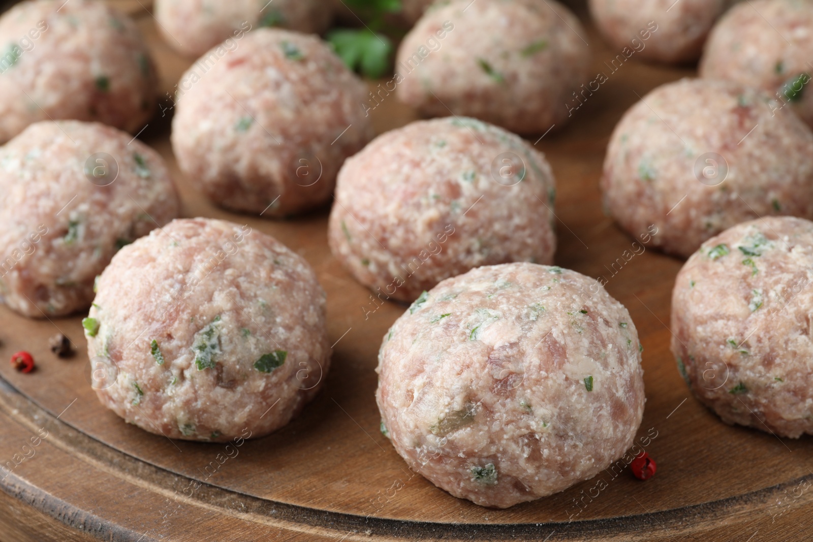 Photo of Many fresh raw meatballs on wooden board, closeup