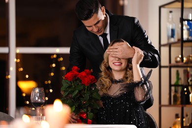 Photo of Man presenting roses to his beloved woman in restaurant at Valentine's day dinner