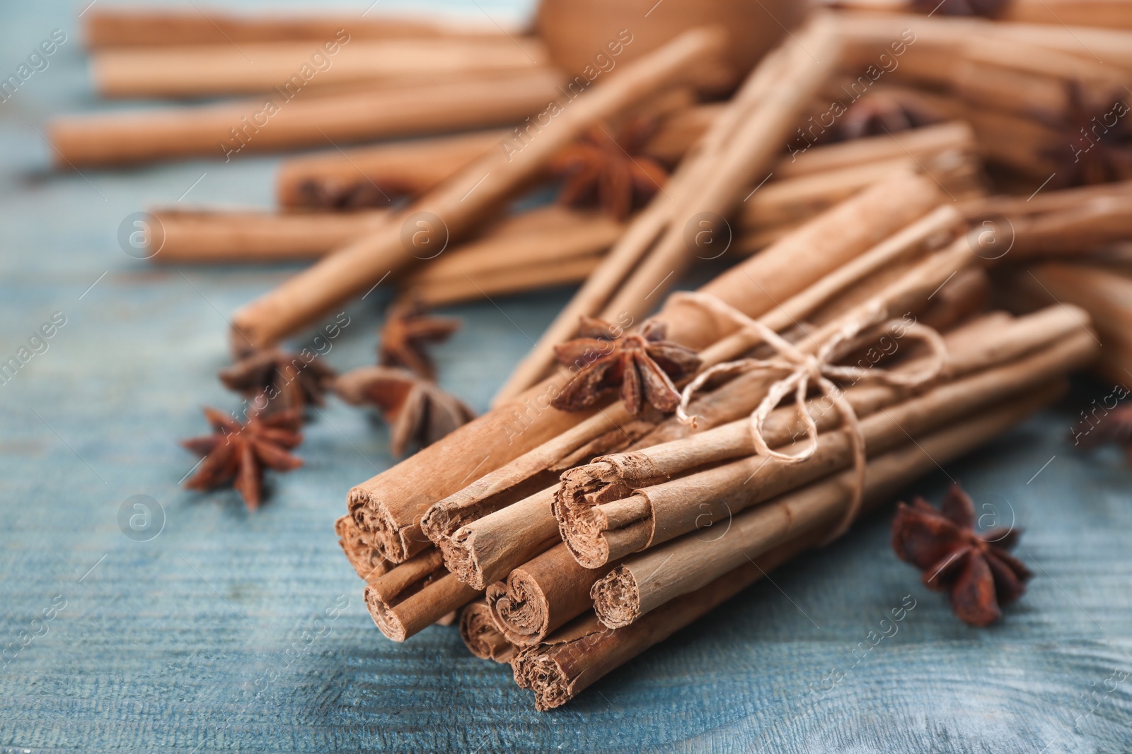 Photo of Aromatic cinnamon sticks and anise on blue wooden table, closeup