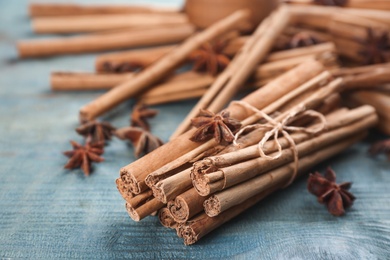 Aromatic cinnamon sticks and anise on blue wooden table, closeup