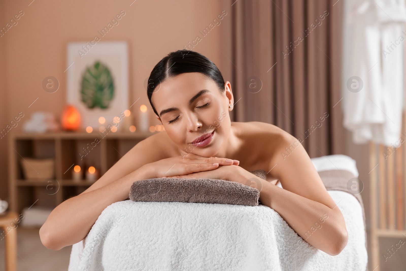 Photo of Young woman resting on massage couch in spa salon