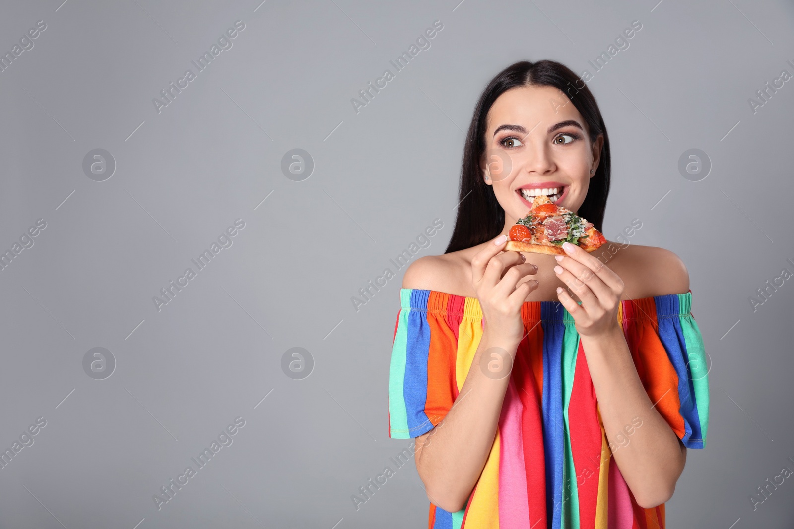Photo of Beautiful woman eating pizza on grey background, space for text