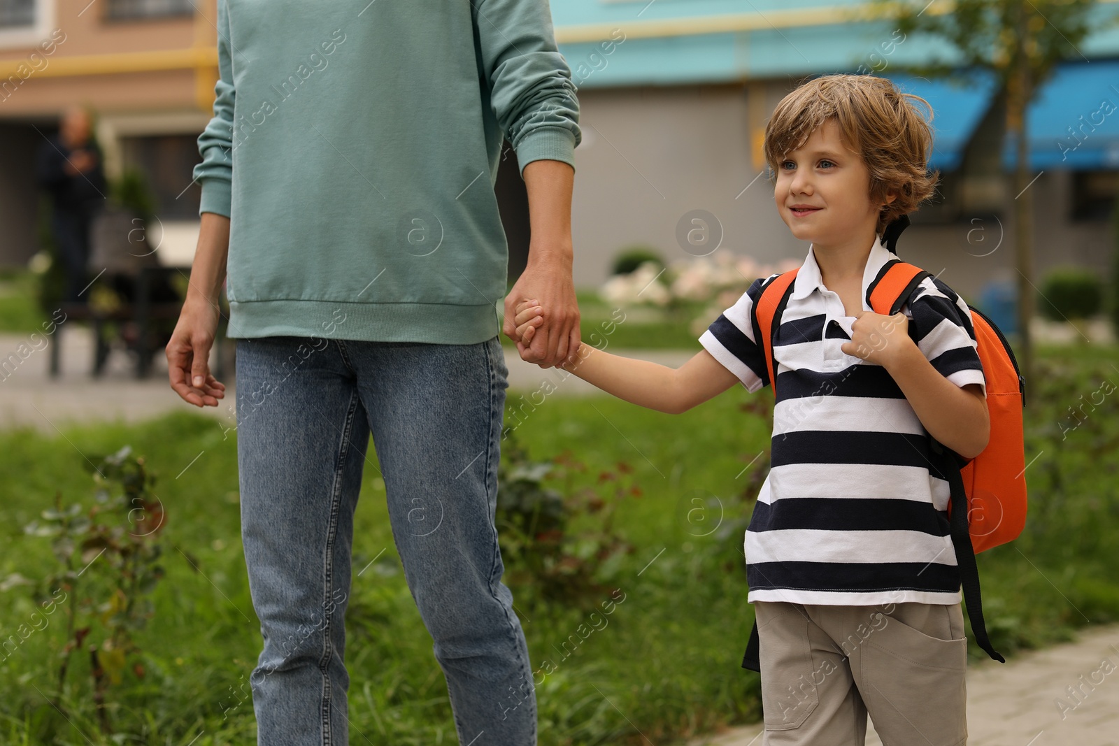 Photo of Woman and her little son on their way to kindergarten outdoors, closeup