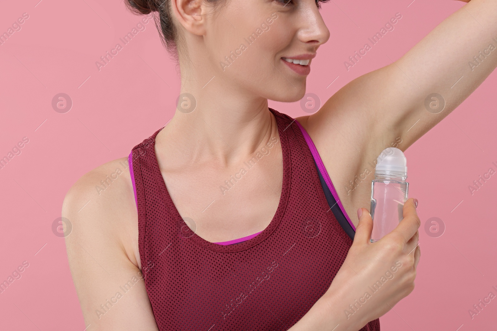 Photo of Beautiful woman applying deodorant on pink background