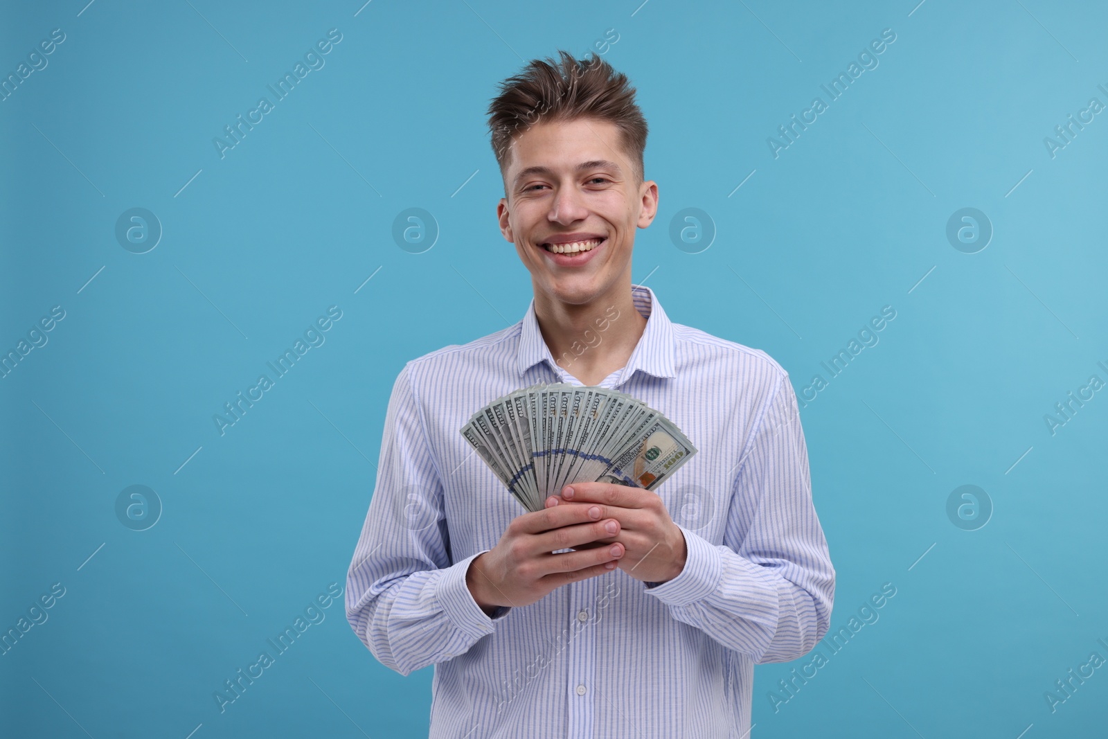 Photo of Happy man with dollar banknotes on light blue background