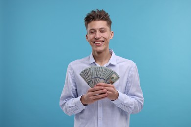 Photo of Happy man with dollar banknotes on light blue background