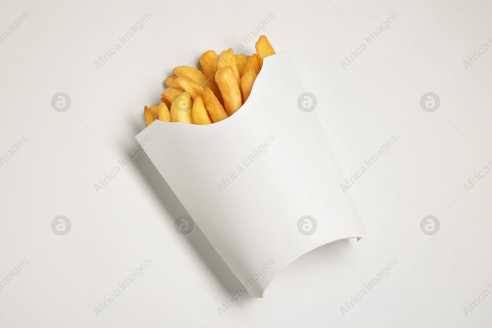 Photo of Paper cup with French fries on white table, top view