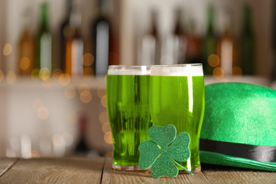 Photo of Green beer, clover and hat on wooden counter, space for text . St.Patrick's Day celebration