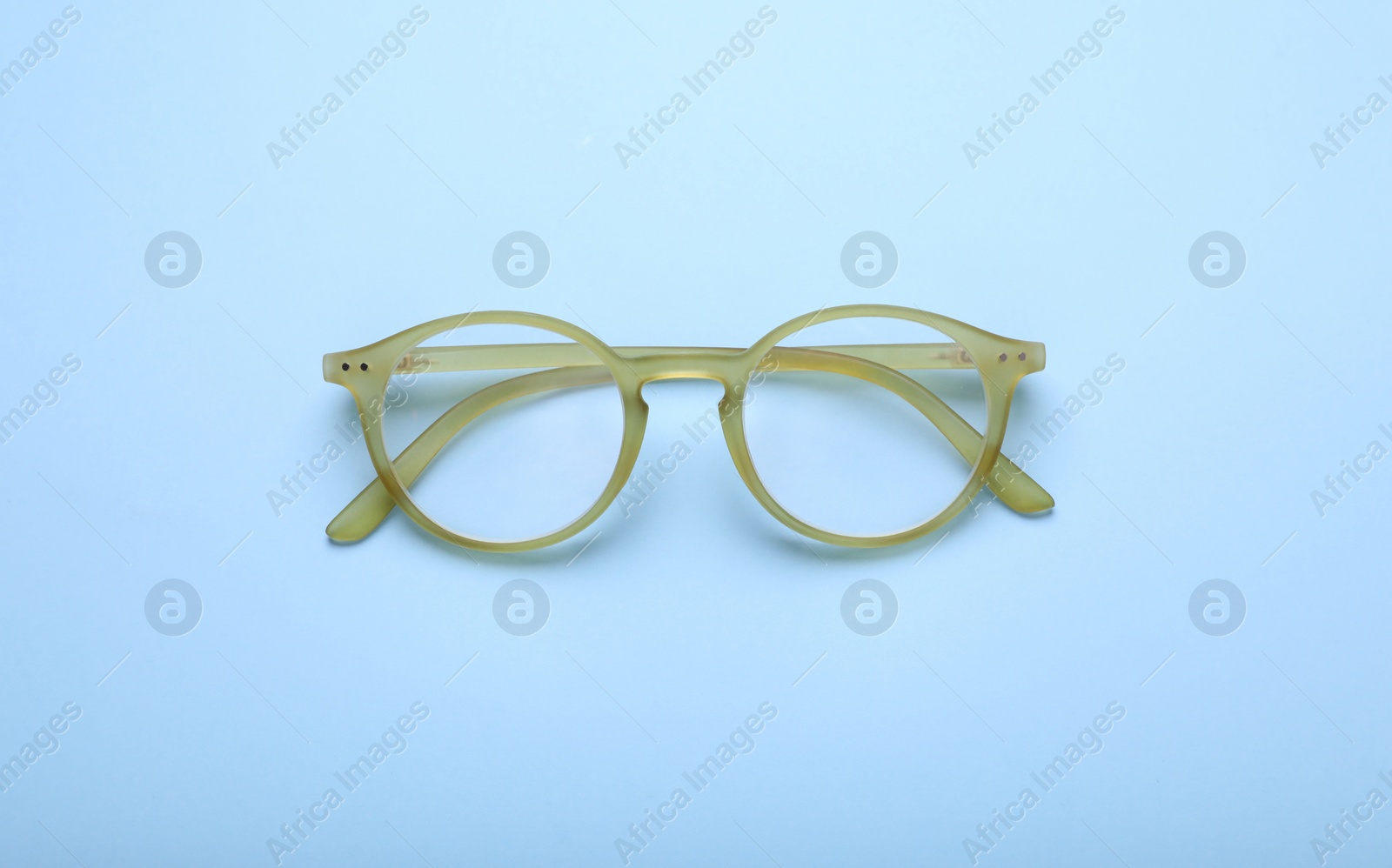 Photo of Glasses with corrective lenses on light blue background, top view