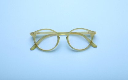 Photo of Glasses with corrective lenses on light blue background, top view