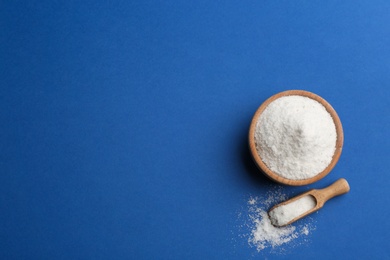 Bowl and scoop with salt on blue background, flat lay. Space for text