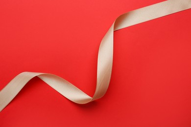 Beautiful ribbon on red background, top view