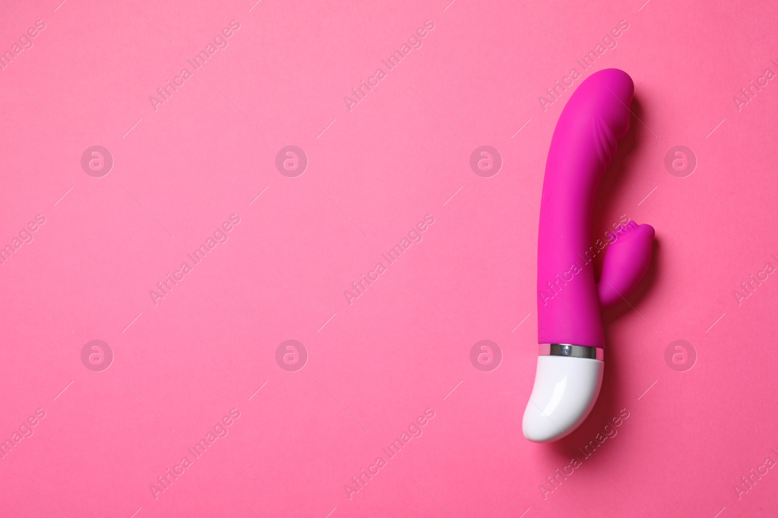 Photo of Dildo on pink background, top view with space for text. Sex toy