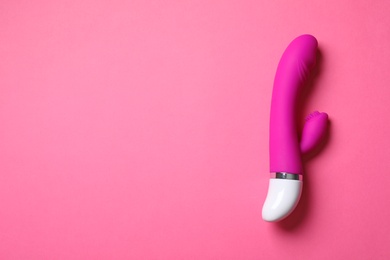 Photo of Dildo on pink background, top view with space for text. Sex toy