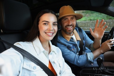 Happy couple taking selfie while enjoying trip together by car