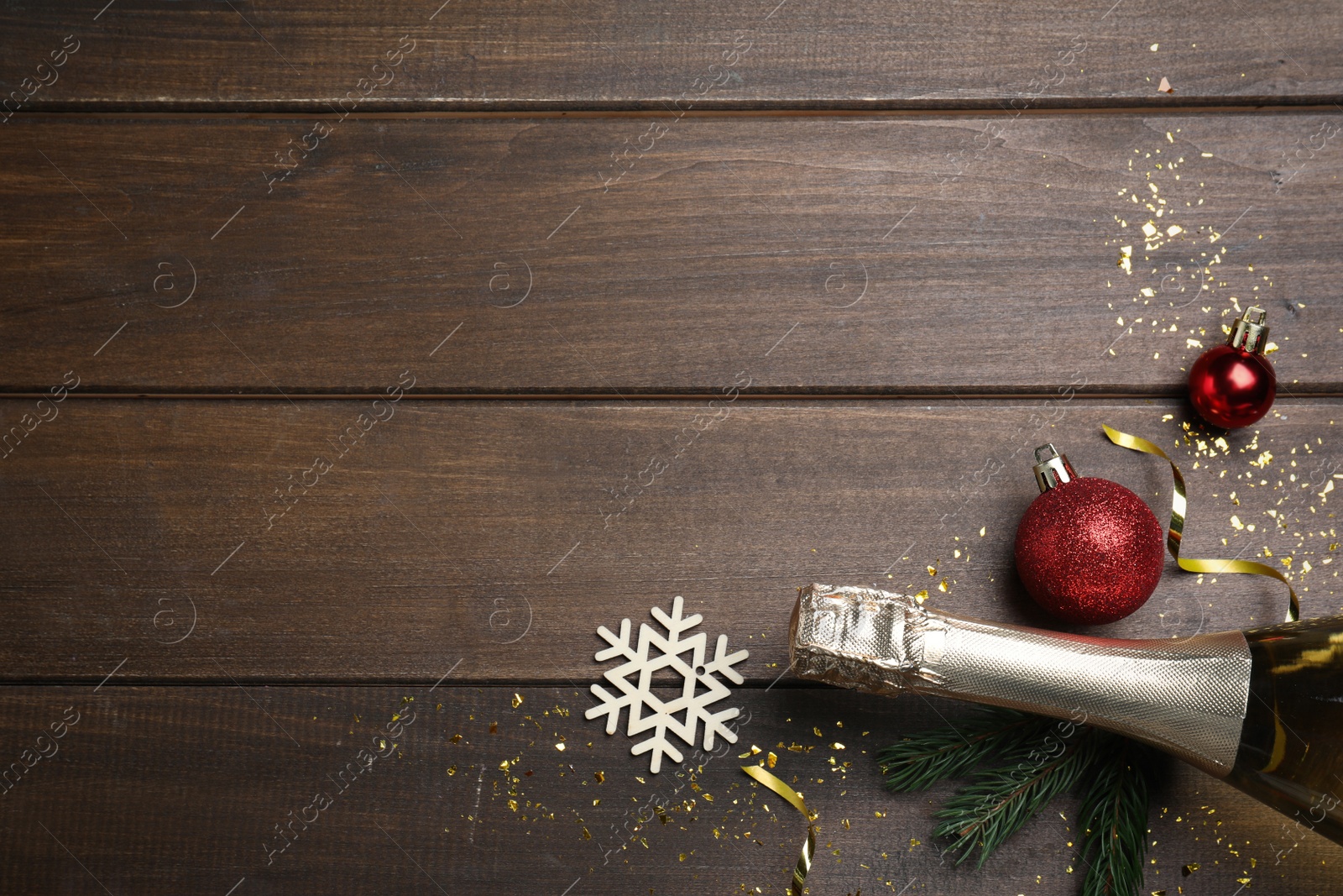 Photo of Flat lay composition with bottle of sparkling wine and festive decor on wooden background, space for text. Happy New Year