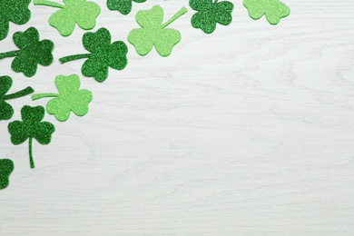 Decorative clover leaves on white wooden table, flat lay with space for text. Saint Patrick's Day celebration