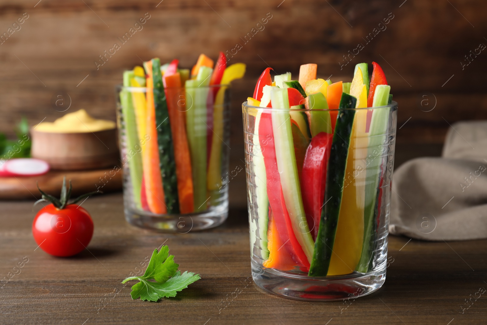 Photo of Fresh raw vegetable sticks in glasses on wooden table