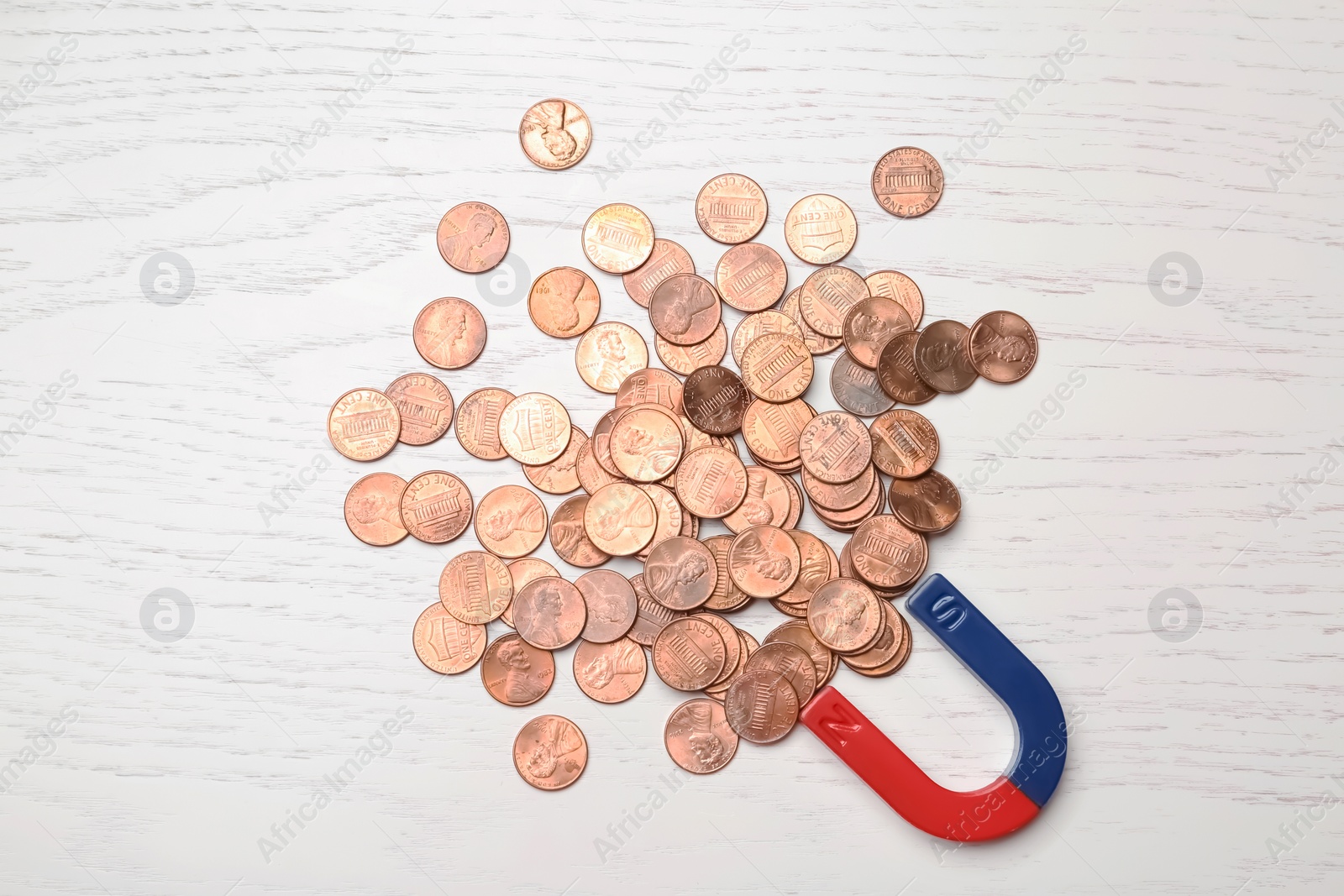 Photo of Magnet attracting coins on wooden background, top view. Business concept