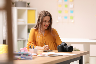Photo of Young journalist with camera at table in office