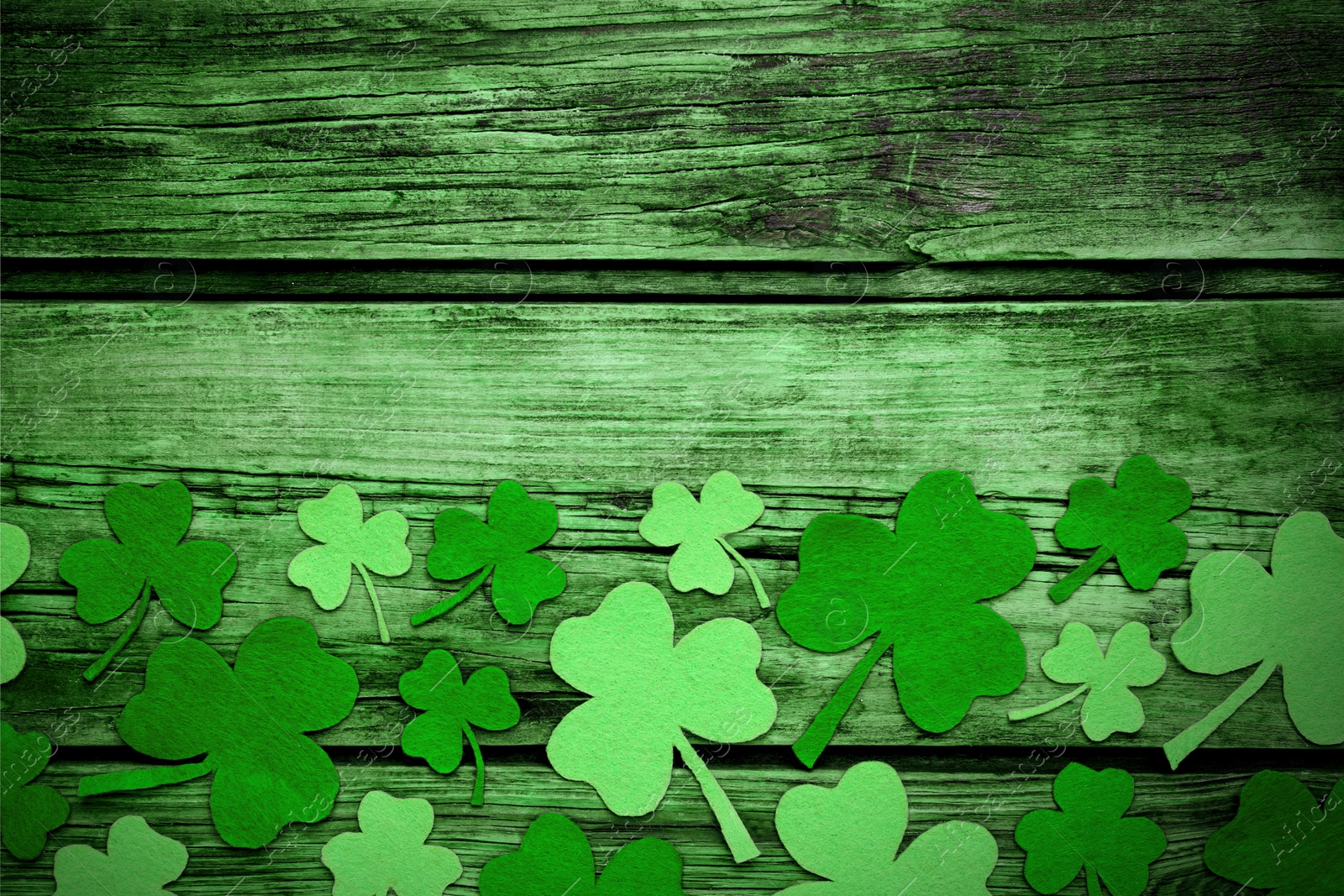 Image of Decorative clover leaves on green wooden background, flat lay with space for text. St. Patrick's Day celebration