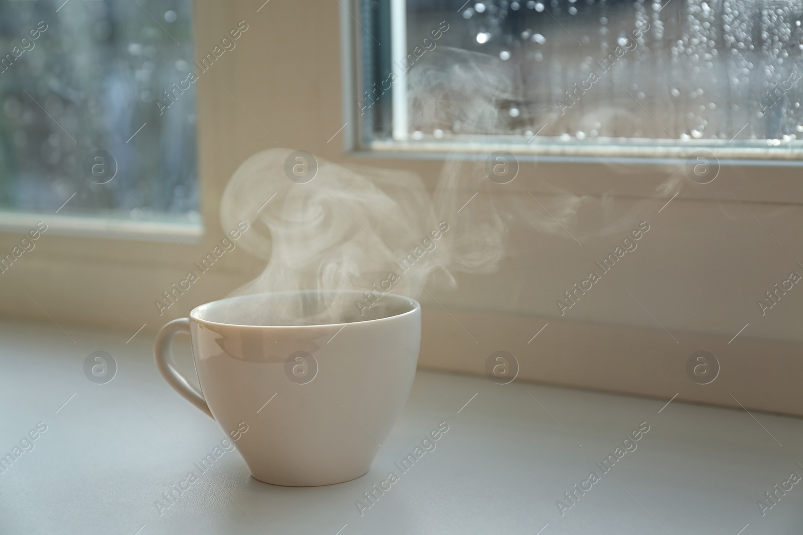 Photo of Cup of hot drink near window on rainy day.  Space for text