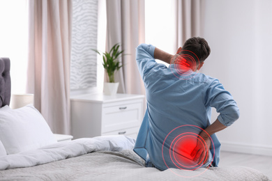 Man suffering from back pain after sleeping on uncomfortable mattress at home