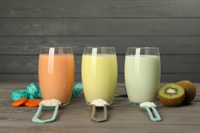 Photo of Tasty shakes, different powders, measuring tape, cut carrot and kiwi on wooden table. Weight loss