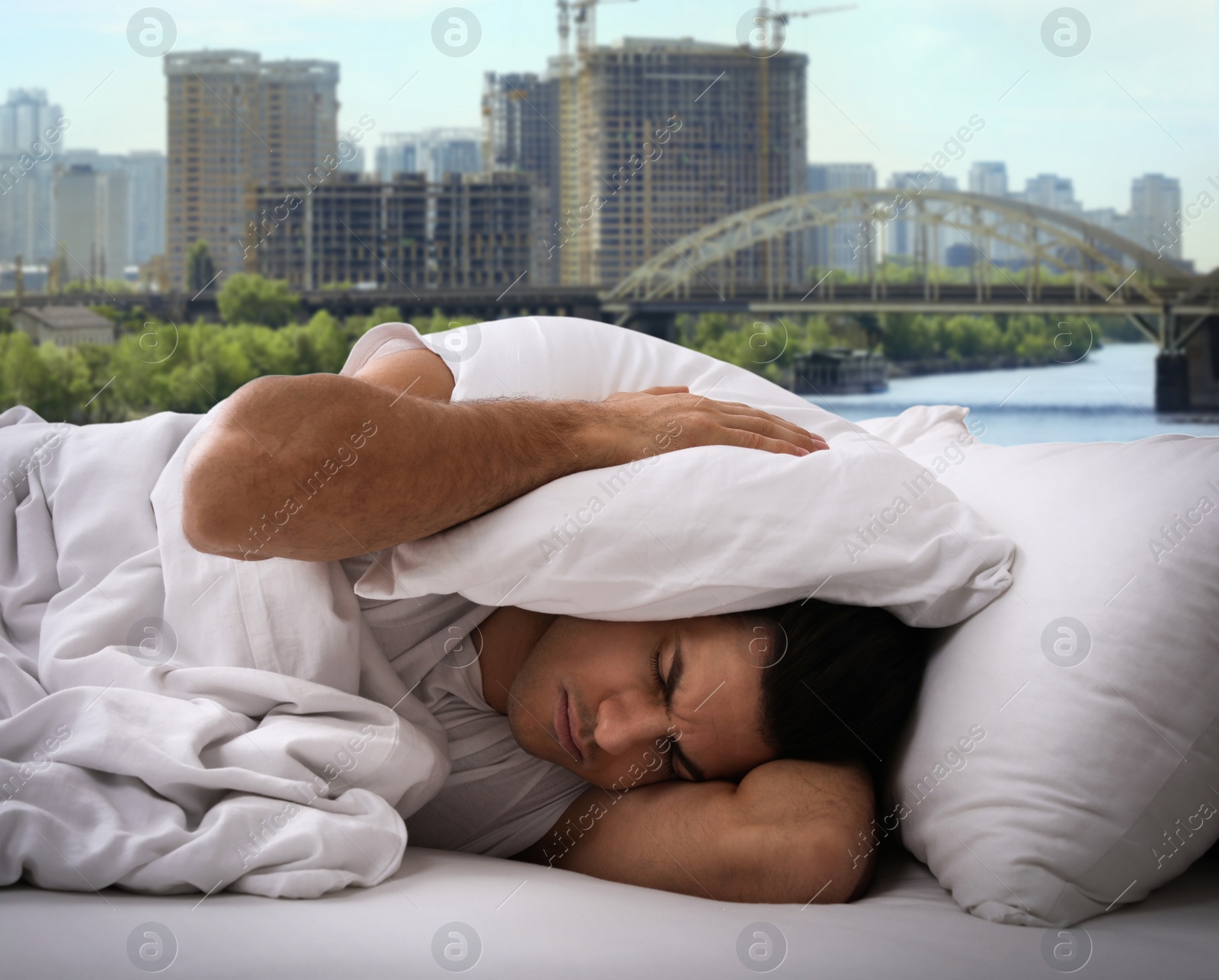 Image of Man in bed and beautiful view of cityscape on background. Poor sleep because of urban noise