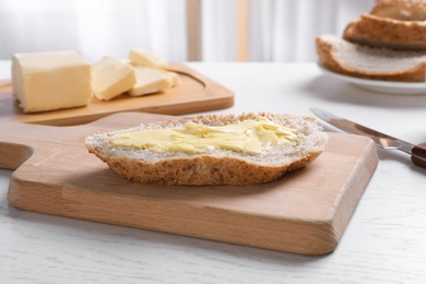 Photo of Fresh bread with tasty butter on wooden board