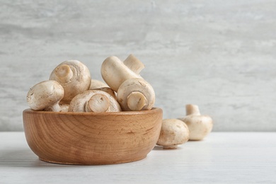 Photo of Bowl with fresh champignon mushrooms on wooden table, space for text