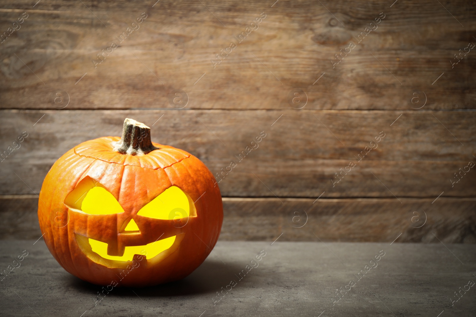 Photo of Scary jack o'lantern pumpkin on wooden background, space for text. Halloween decor