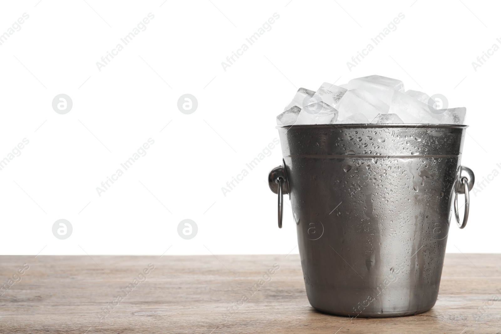 Photo of Metal bucket with ice cubes on wooden table against white background